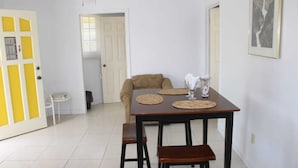 Un coin repas avec une table dressée pour deux personnes, un canapé et une petite table d’appoint.