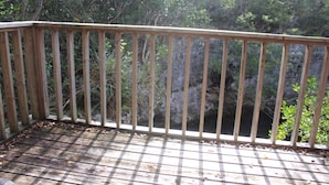 Une terrasse en bois dotée d’une rambarde, qui offre une vue sur un paysage naturel.