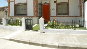 A two-story house with a red door, white walls, and a brick facade.
