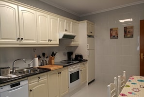 Keittiössä on valkoiset kaapit, astianpesukone, liesi ja kahvinkeitin.