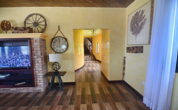 A living room with a television, a clock, and a staircase leading to another room.
