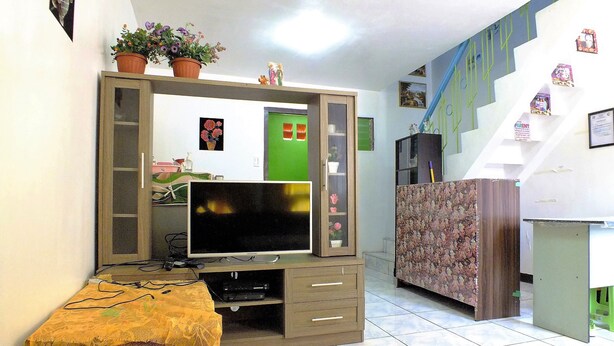 Una sala de estar con televisión, mueble de entretenimiento y una escalera.