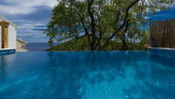 Relax by the serene pool surrounded by lush greenery and a stunning sea view.