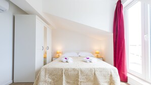 Une chambre à coucher avec un grand lit, deux lampes de chevet, une armoire et une fenêtre avec un rideau rouge.