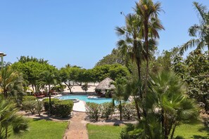 A pool surrounded by lush greenery and palm trees, with a thatched-roof structure nearby. - 3BR Condo 421: Dual Balconies, Sea View,Sleeps 6 (Seine Bight)