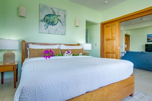 A bedroom with a bed, a wooden headboard, a wall-mounted artwork of a turtle, and a door leading to another room. - 3BR Condo 421: Dual Balconies, Sea View,Sleeps 6 (Seine Bight)