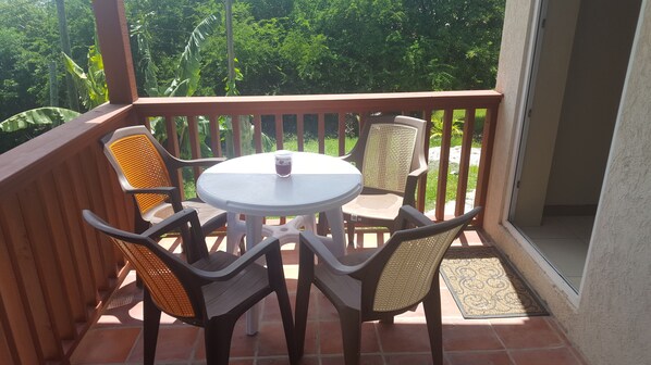 A small outdoor patio with a round table and four chairs, surrounded by a wooden railing.