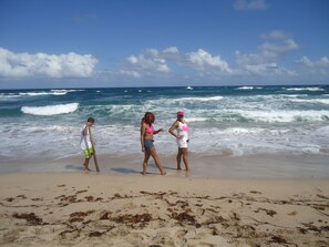 A beach with three people walking along the shore.