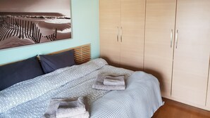 Une chambre à coucher avec un lit, une armoire et un tableau accroché au mur.