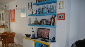 A room with a white cabinet, a computer monitor, and a shelf with various items. - House of the rose. An explosion of color and beauty in a still virgin landscape. (Nijar)