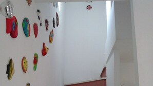 A staircase with red steps leading upwards, surrounded by a white wall adorned with various colorful fish and sea creature decorations. - House of the rose. An explosion of color and beauty in a still virgin landscape. (Nijar)