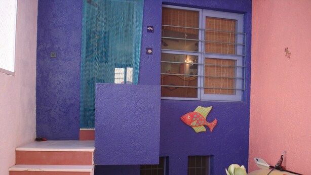 A building with a purple exterior, a fish decoration, and a staircase leading to a window. - House of the rose. An explosion of color and beauty in a still virgin landscape. (Nijar)