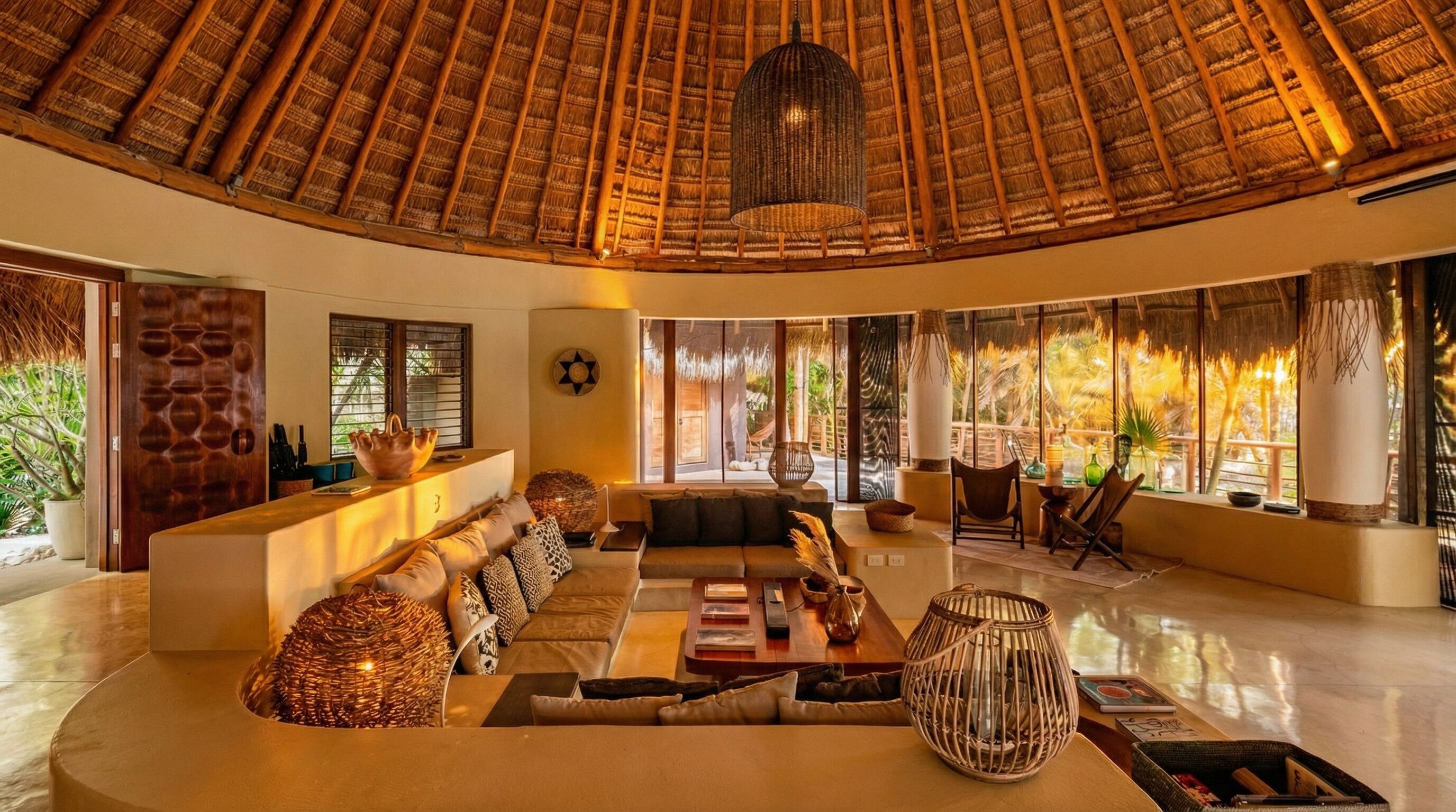 A spacious living area with a thatched roof, a sofa set, a coffee table, and a dining table.