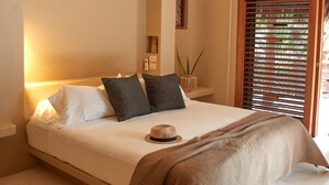 Une chambre à coucher avec un lit, des oreillers, un chapeau et un ventilateur de plafond.