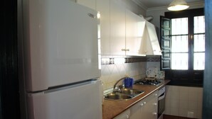 Een keuken met een koelkast, spoelbak, kookplaat en vaatwasser.