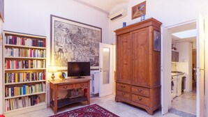 A living room with a bookshelf, a television, a wooden cabinet, and a patterned rug.