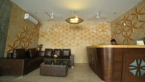 A reception area with a patterned wall, a reception desk, leather seating, and a ceiling fan. - Lariviera falcon nest in Madhapur  (Hyderabad)