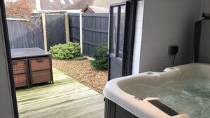 Un bain à remous avec une terrasse carrelée et une clôture en bois en arrière-plan.
