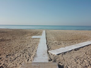 A beach with a wooden walkway leading to the sea.