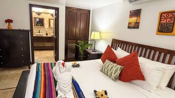 A hotel room with a bed, a nightstand, a lamp, a mirror, and a door leading to a bathroom.