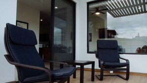A modern room with two dark-colored chairs and a small table, large windows with a view of the city, and a ceiling fan. - The Best Vacation Place in the Heart of Ensenada with Panoramic view (Ensenada)