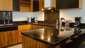 A modern kitchen with wooden cabinets, a black countertop, and stainless steel appliances including a microwave, toaster, and coffee maker. - The Best Vacation Place in the Heart of Ensenada with Panoramic view (Ensenada)
