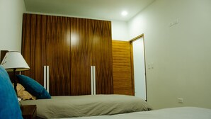 A bedroom with two beds, a wooden wardrobe, and a nightstand with a lamp. - The Best Vacation Place in the Heart of Ensenada with Panoramic view (Ensenada)
