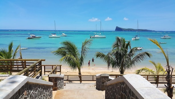 Una playa con aguas turquesas cristalinas, barcos y palmeras.