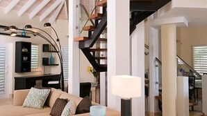 Una sala de estar moderna con techo alto, una escalera y un sofá.