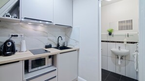 Een moderne keuken met een magnetron, waterkoker en spoelbak.