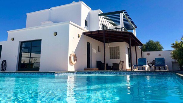 A modern building with a swimming pool, a covered patio, and a clear blue sky. - 4 Bedroom, 3 Bathroom, Large Heated Pool, 20 Minute Walk to Playa Blanca Town (Playa Blanca)