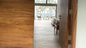 A wooden door leading to a room with a view of the outdoors, a sofa, and a coffee table.