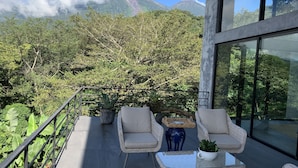 A balcony with wicker furniture, a potted plant, and a view of a mountain.