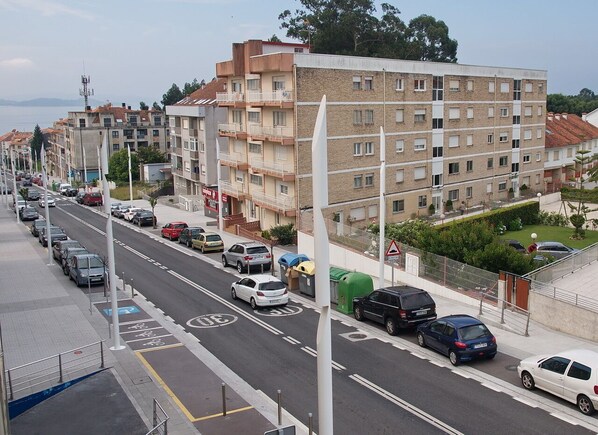 A street lined with parked cars and a row of multi-story residential buildings.