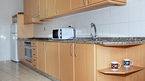 Una cocina con armarios de madera, microondas, fregadero y encimera.
