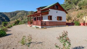 A two-story house with a red roof and white walls, surrounded by a gravel driveway and greenery. - House with Private Pool (Piscis) (Arenas)