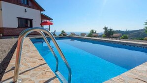 A swimming pool with a stone border, a metal ladder, and lounge chairs. - House with Private Pool (Piscis) (Arenas)