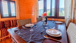 A wooden cabin dining area with a table set for four, two cushioned benches, and large windows with curtains. - House with Private Pool (Piscis) (Arenas)