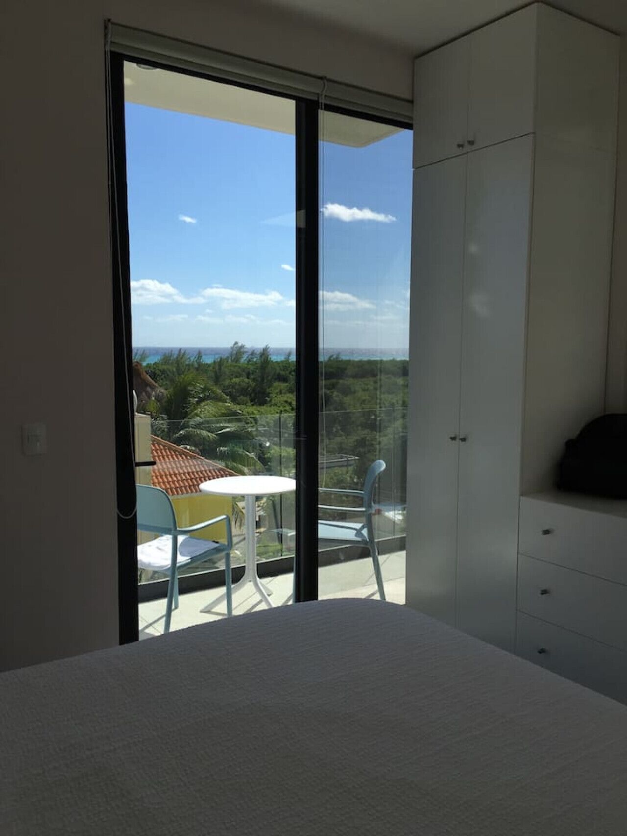 Un balcon avec une porte-fenêtre, une petite table et deux chaises.