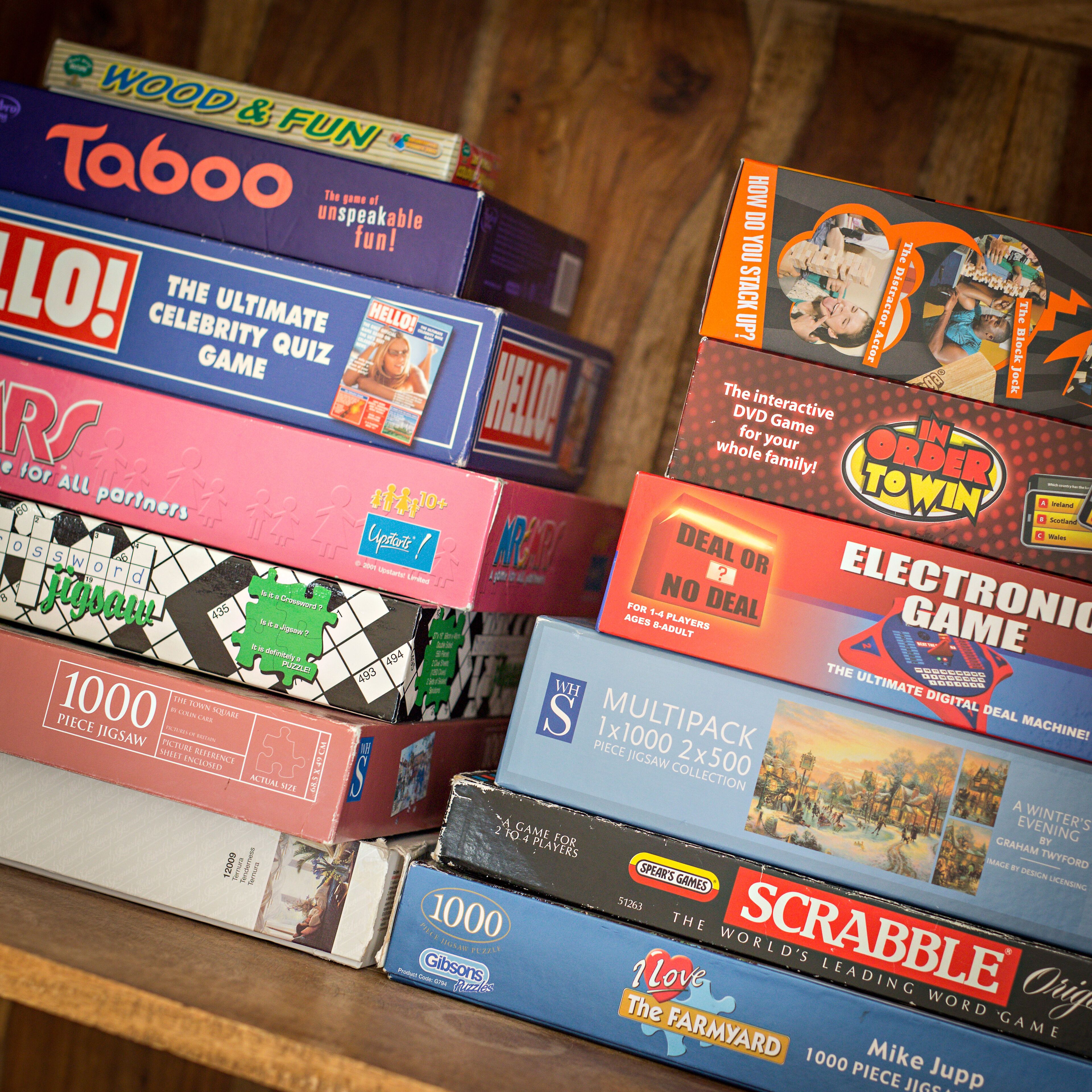 A variety of board games stacked on a shelf.