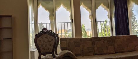 A living room with a sofa, a chair, and a large window with decorative glass panes.