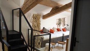 Ein modernes Schlafzimmer mit einer Holztreppe, einem Bett mit vielen Kissen und einem kleinen Holztisch.