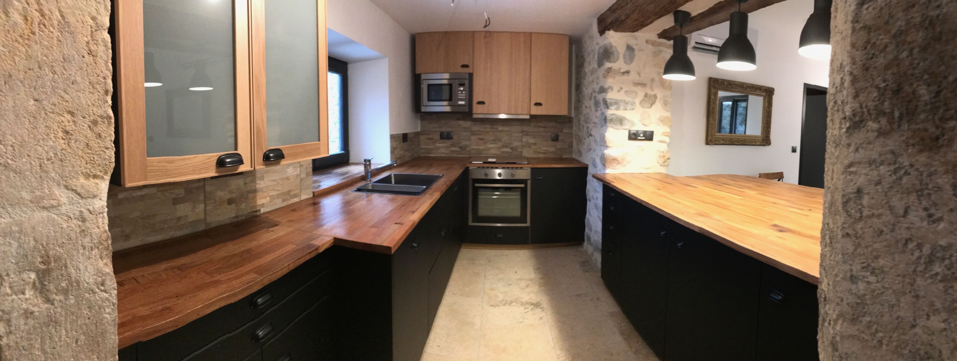 A compact kitchen with wooden countertops, a built-in oven, and a stone accent wall.