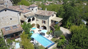 Eine Steinvilla mit Swimmingpool, Sitzgelegenheit im Freien und Blick auf das umliegende Dorf.