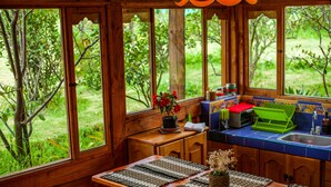 A wooden cabin kitchen with large windows, a sink, and a table with woven placemats.