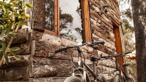A rustic log cabin with a bicycle parked outside.