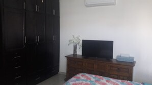 Een slaapkamer met een bed, een dressoir, een televisie en een kledingkast.