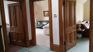 A hallway with wooden doors leading to a living area with a sofa and a lamp. - Sea View Apartment with commanding sea views in Crail (Crail)
