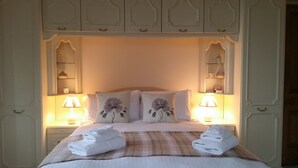 A neatly made bed with two pillows, a plaid blanket, and two folded towels on the foot of the bed. There are two bedside lamps on either side of the bed. - Sea View Apartment with commanding sea views in Crail (Crail)