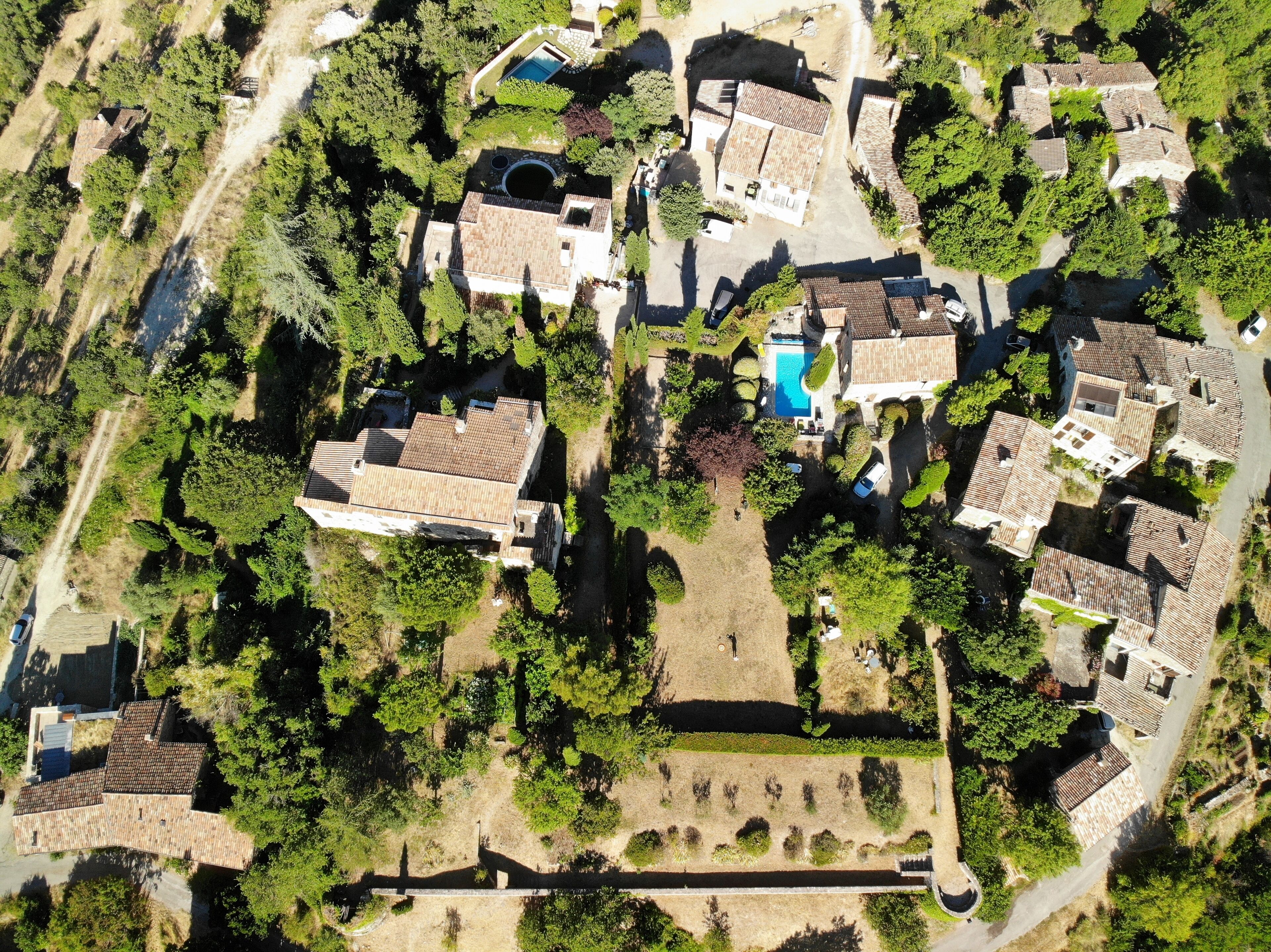 An aerial view of a residential area with multiple houses, a swimming pool, and well-maintained gardens.